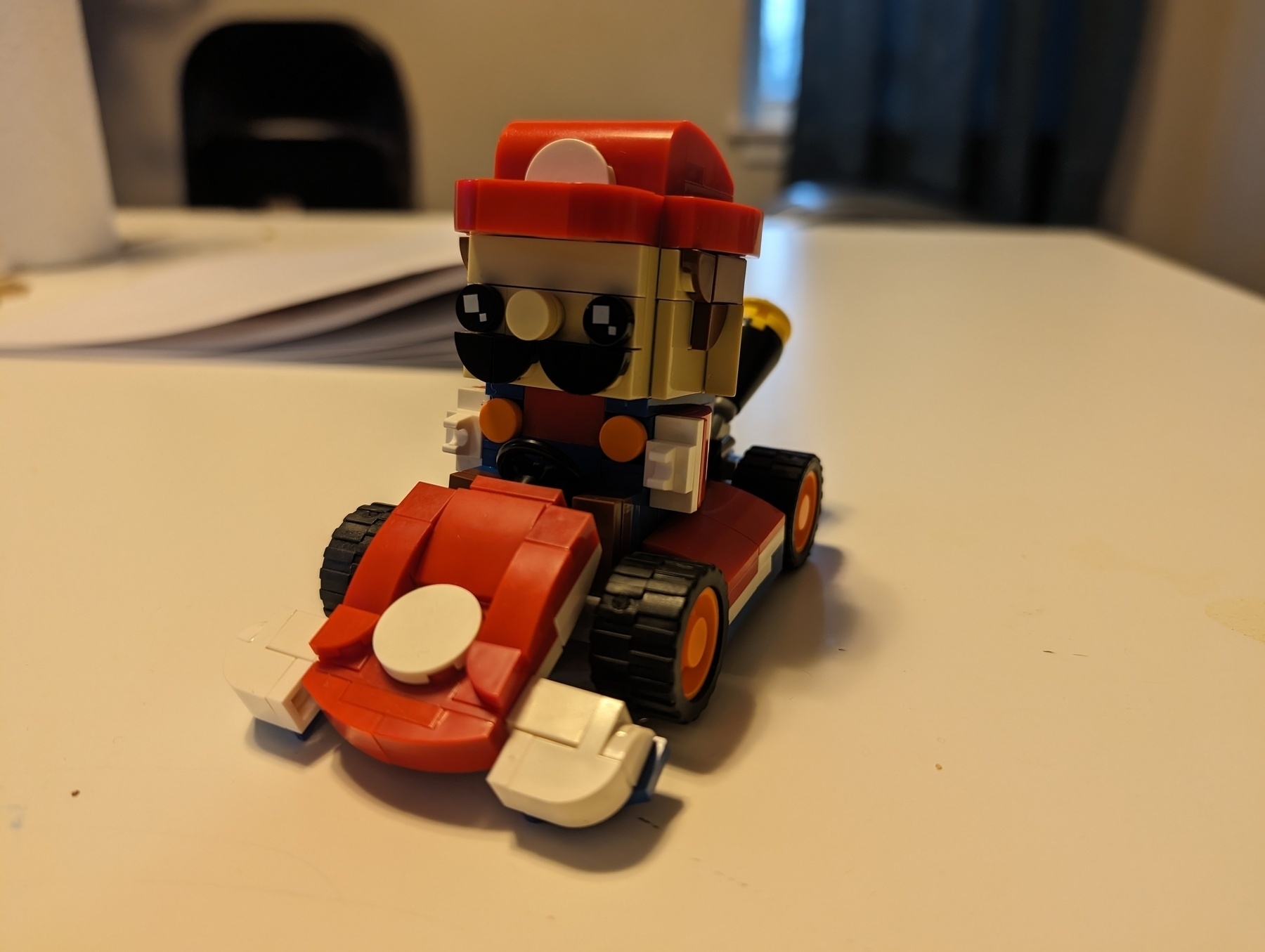 Photo of a figure built out of a brick building system, in the style of a popular character that can sit in a go cart. Any resemblance to any known character is purely coincidental.