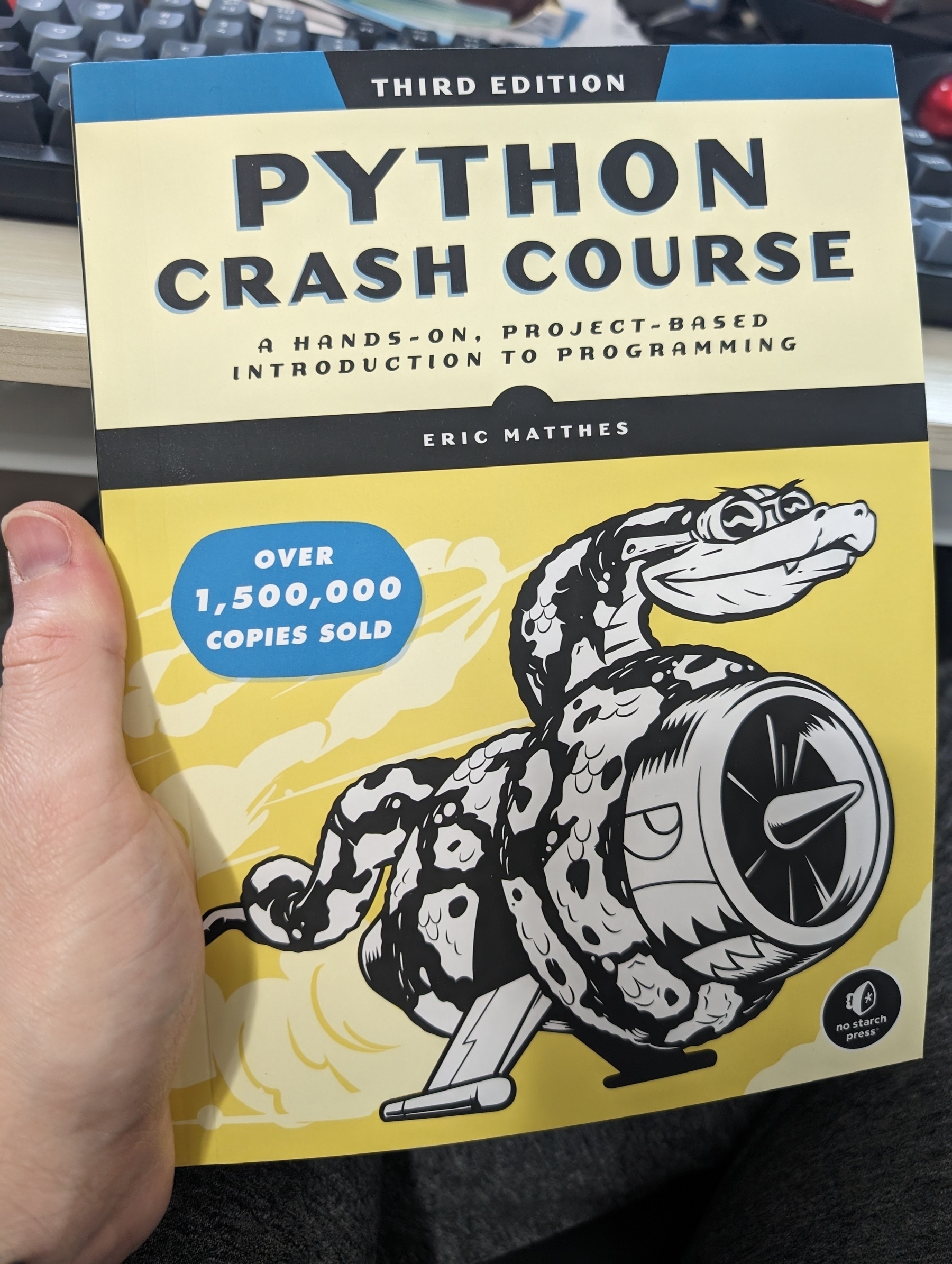 Photo of the book "Python Crash Course: A hands on, projects based introduction to programming", third edition, by Eric Matthews.