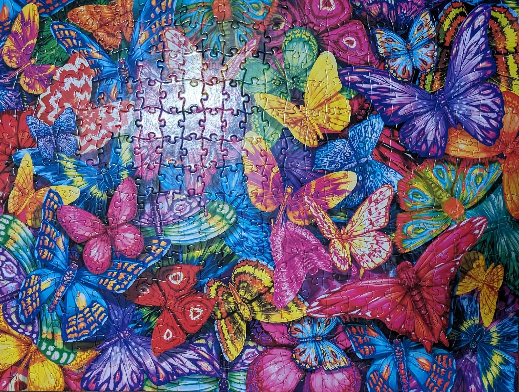 Photo of a puzzle featuring a multitude of colorful butterflies. There is an imperfection in the photo in the form of a light glare.