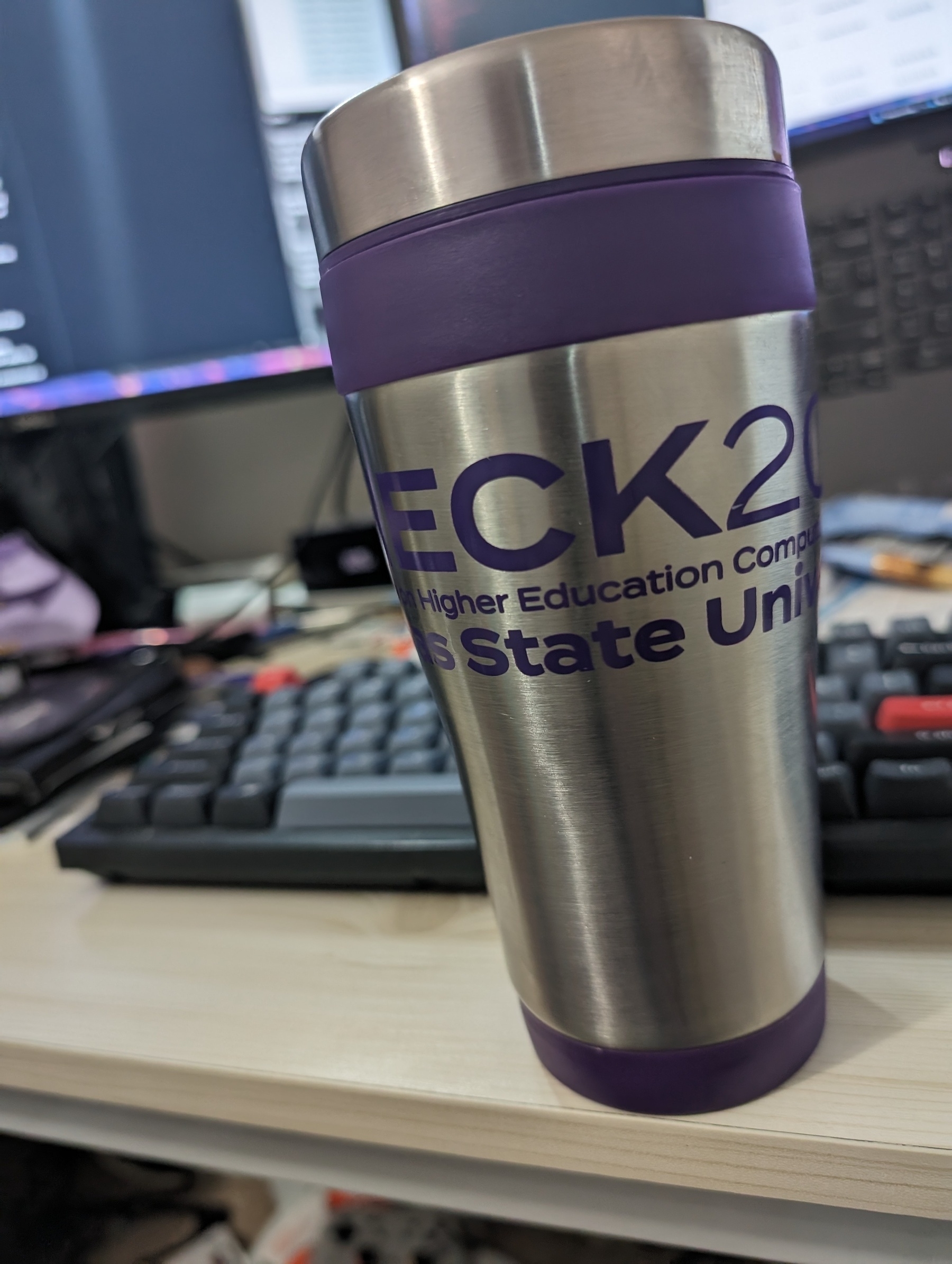 Photo of the author's coffee mug. The lettering, in a purple font reads (in total): "CHECK 2018 Conference on Higher Education Computing in Kansas, Kansas State University"